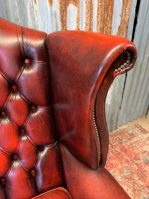 An oxblood wingback Queen Anne-style armchair