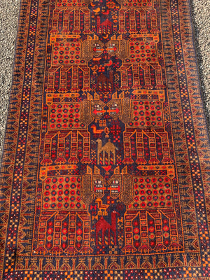 A rectangular red ground Belouch Herat rug depicting lions, camels and birds