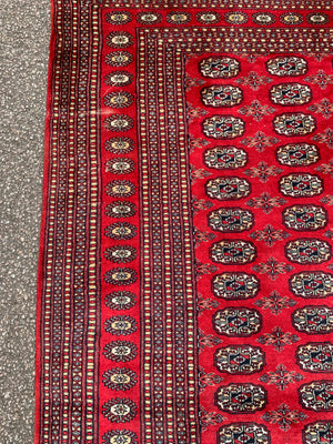 A large red ground Bokhara rectangular rug ~ 282cm x 186cm