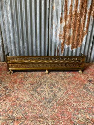 A large Victorian brass fender with lion paw feet