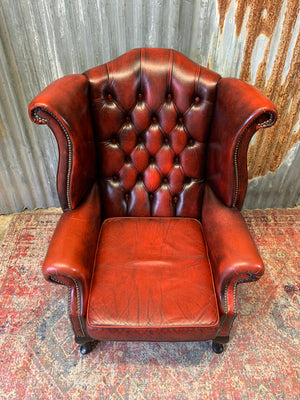 An oxblood wingback Queen Anne-style armchair