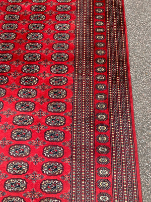 A large red ground Bokhara rectangular rug ~ 282cm x 186cm