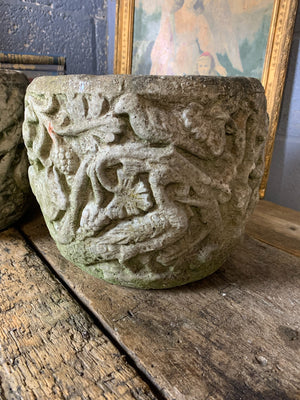 A pair of large cast stone urns with flora and fauna detailing