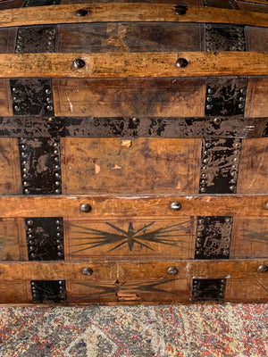 An oak dome top steamer trunk with tooled leather motifs