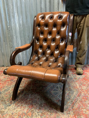 A brown leather button back slipper chair