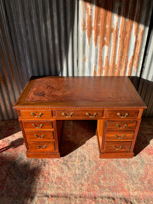 A pedestal desk with red leather top