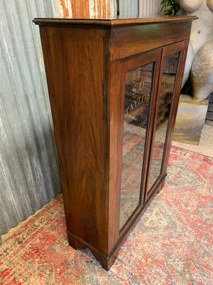 A wooden apothecary style cabinet with glass doors