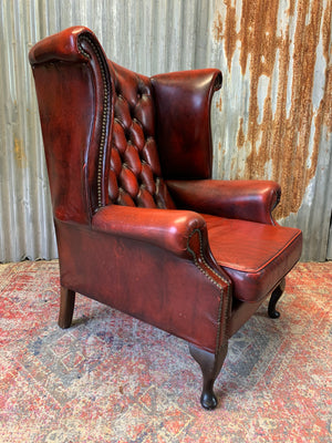 An oxblood wingback Queen Anne-style armchair