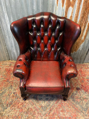 An oxblood wingback Queen Anne-style armchair