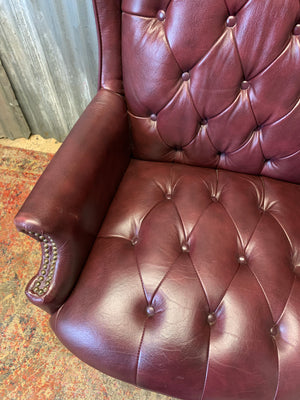 A burgundy leather full button tilt and swivel desk chair
