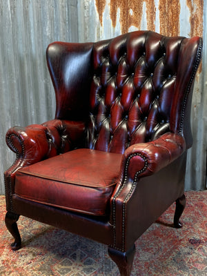 An oxblood wingback Queen Anne-style armchair