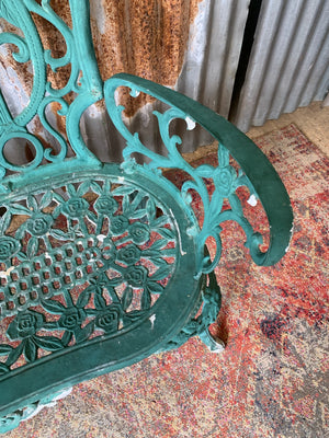 A green cast metal rose motif garden bench