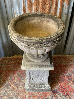 A pair of large cast stone classical urns on pedestals