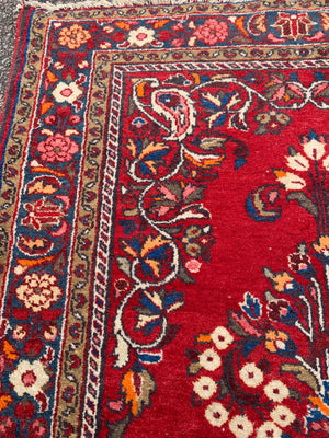 A red ground woolen Persian rug ~ 180cm x 110cm