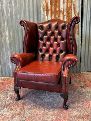 An oxblood wingback Queen Anne-style armchair