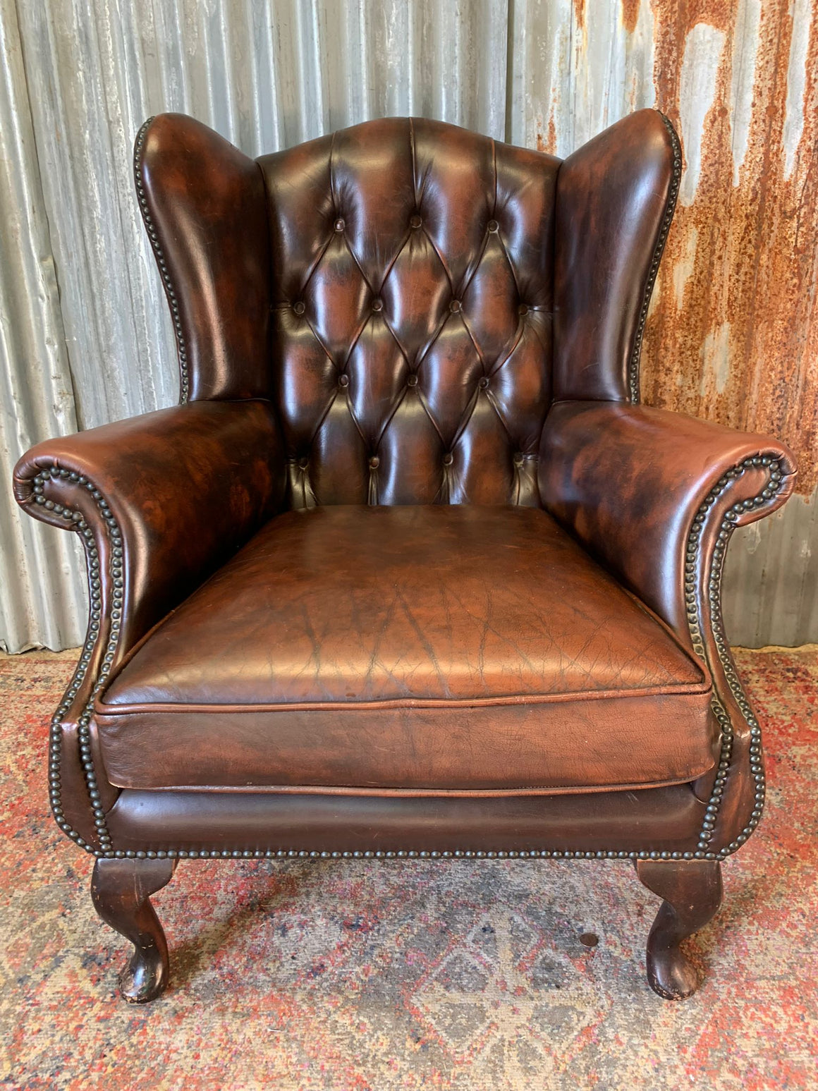 A chocolate brown wingback Queen Anne style armchair