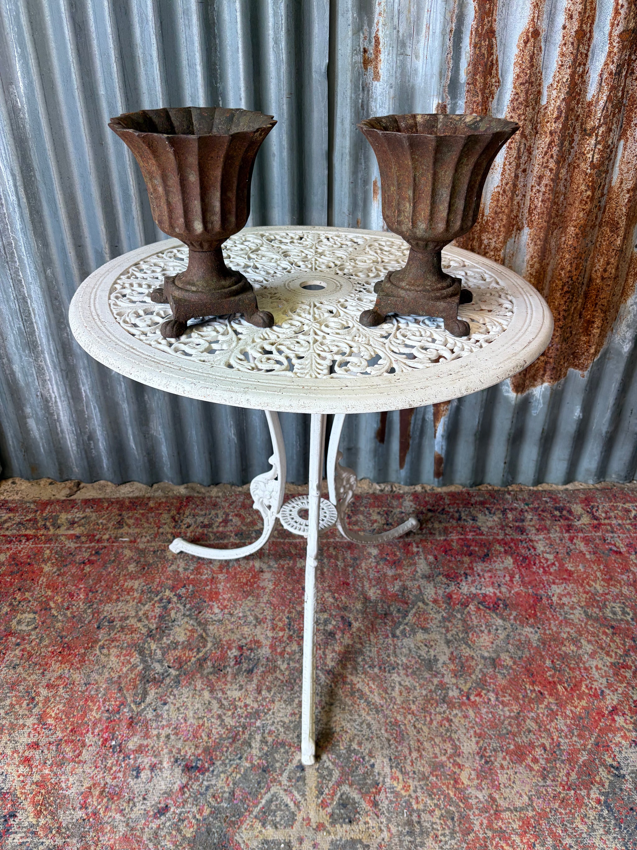 A pair of frilled cast iron urns on paw feet
