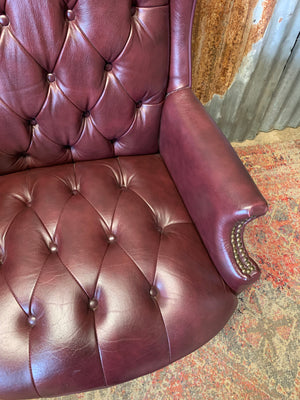 A burgundy leather full button tilt and swivel desk chair
