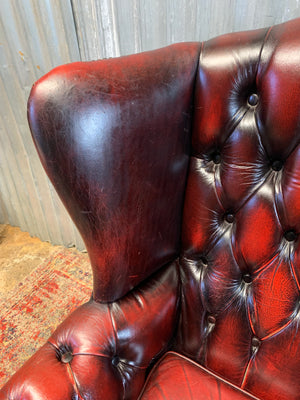 An oxblood wingback Queen Anne-style armchair