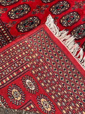 A large red ground Bokhara rectangular rug ~ 282cm x 186cm