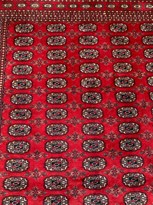 A large red ground Bokhara rectangular rug ~ 282cm x 186cm