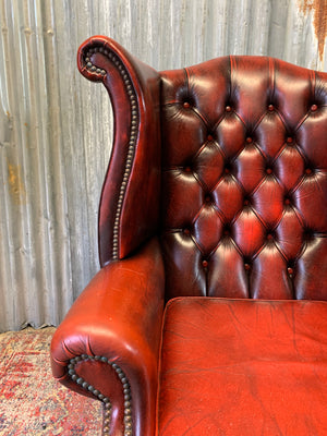 An oxblood wingback Queen Anne-style armchair