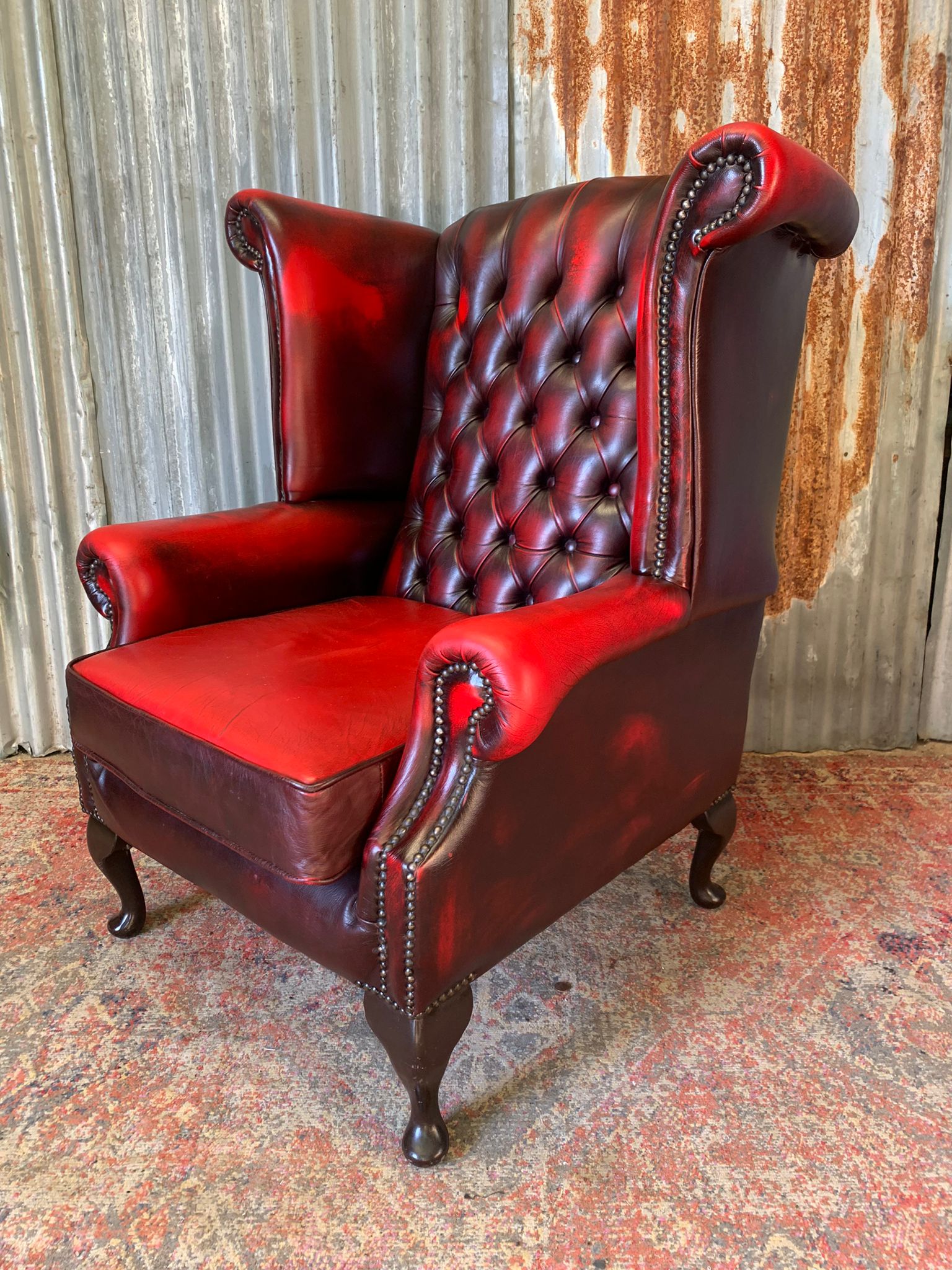An oxblood wingback Queen Anne style armchair