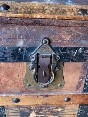 An oak dome top steamer trunk with tooled leather motifs