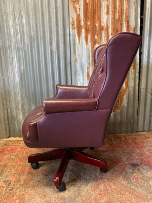 A burgundy leather full button tilt and swivel desk chair