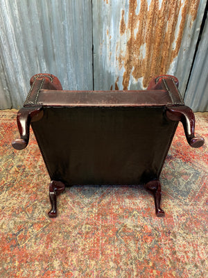 An oxblood wingback Queen Anne-style armchair