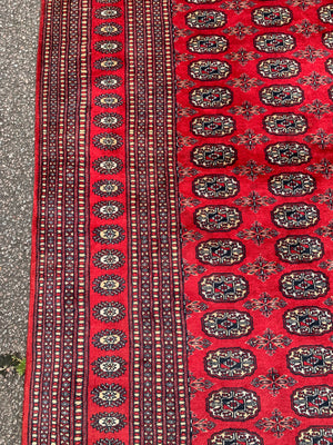 A large red ground Bokhara rectangular rug ~ 282cm x 186cm