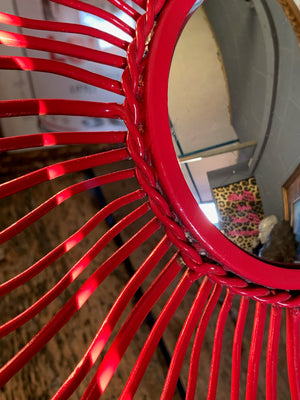 A red metal starburst convex mirror