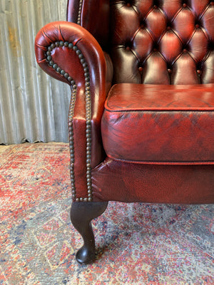 An oxblood wingback Queen Anne-style armchair