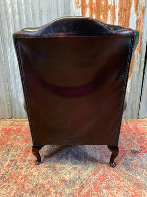 An oxblood wingback Queen Anne-style armchair