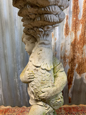 A neoclassical cast stone birdbath with cherub and fish design