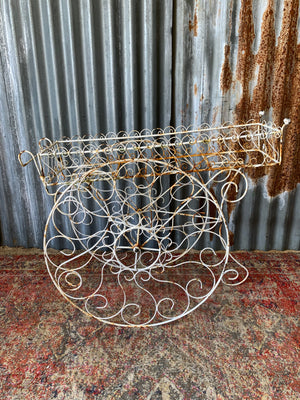 A pair of white wirework barrow plant stands