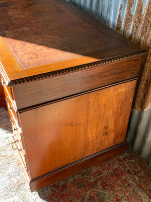 A pedestal desk with red leather top