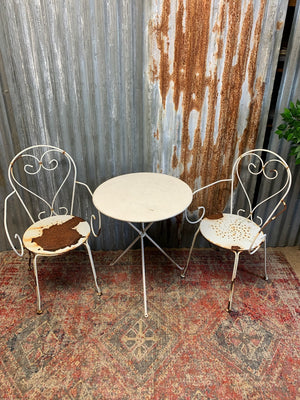 A white French wirework garden set with two chairs and a tripod table
