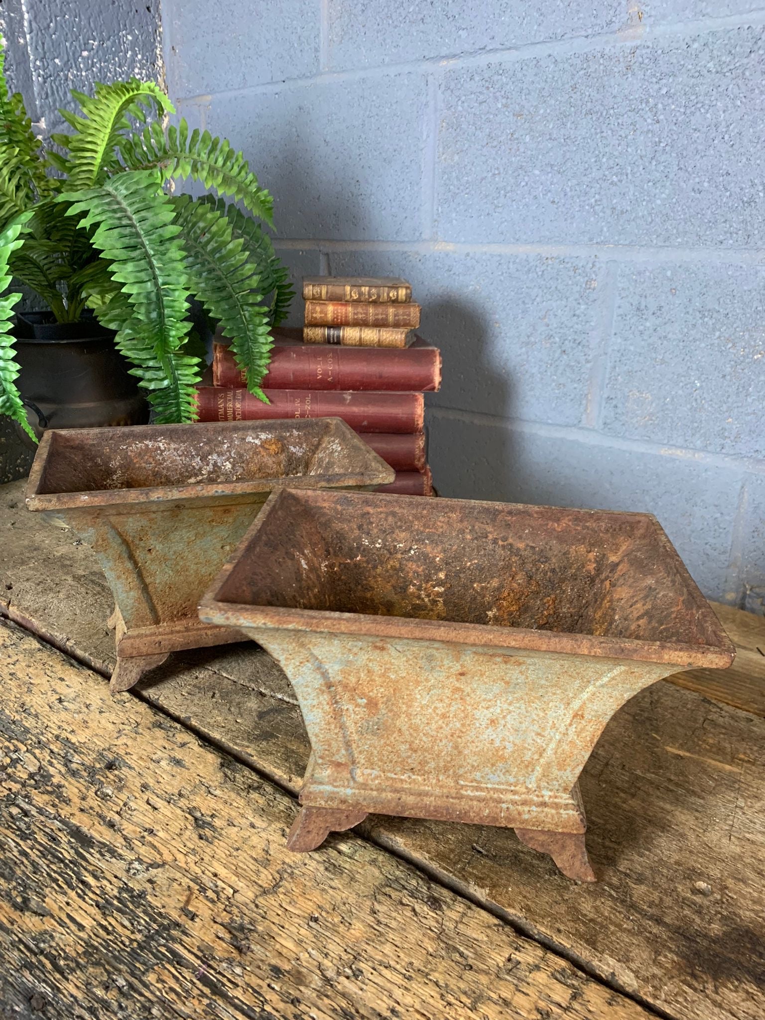 A pair of rectangular cast iron urns on raised feet