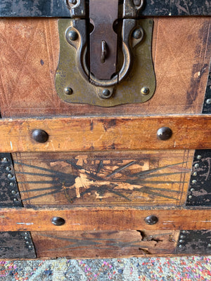 An oak dome top steamer trunk with tooled leather motifs