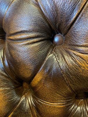 A brown wingback Chesterfield armchair with button back
