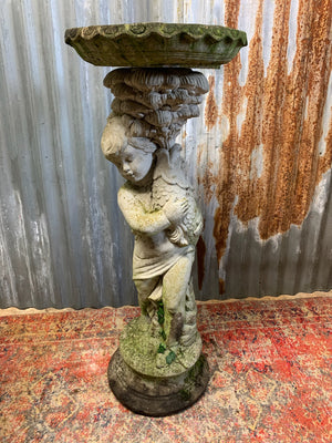 A neoclassical cast stone birdbath with cherub and fish design
