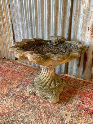 A cast stone bird bath in the form of a shell