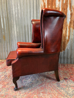 An oxblood wingback Queen Anne-style armchair