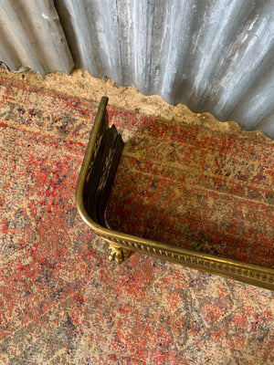 A large Victorian brass fender with lion paw feet