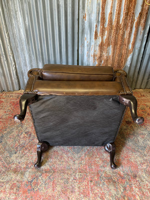 A brown wingback Chesterfield armchair with button back