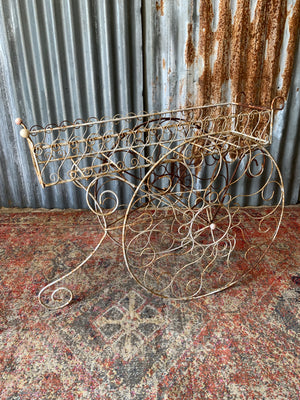 A pair of white wirework barrow plant stands