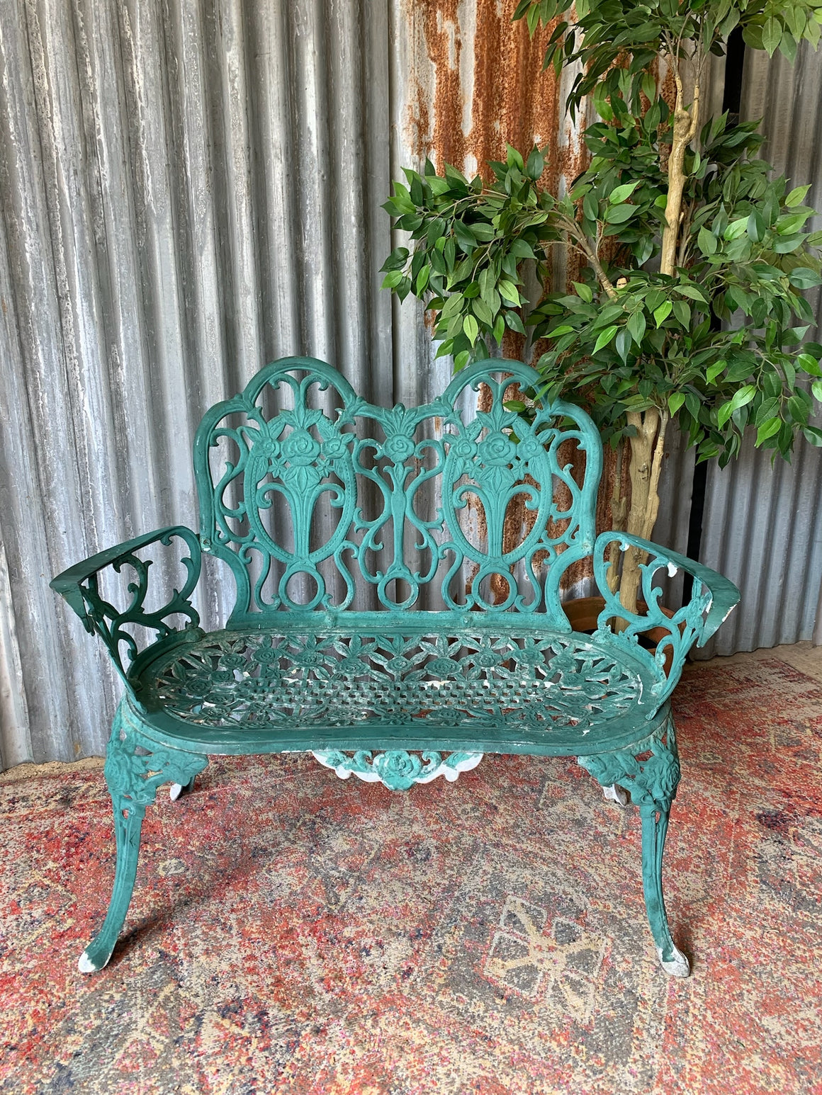 A green cast metal rose motif garden bench