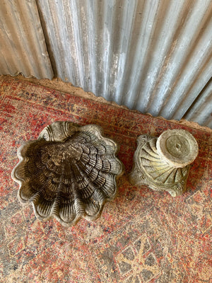 A cast stone bird bath in the form of a shell