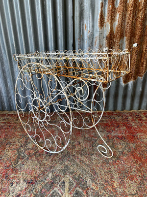 A pair of white wirework barrow plant stands